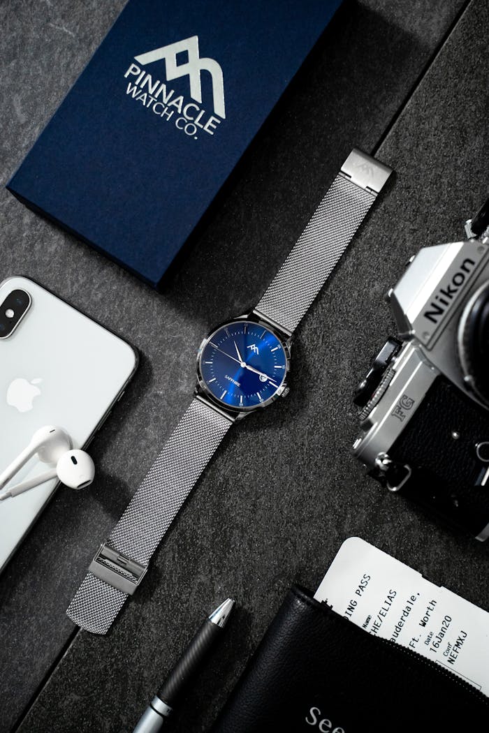 team-02 Stylish flat lay showcasing technology devices, watch, and accessories on dark surface.
